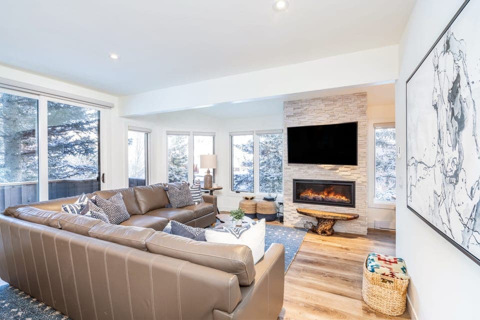 Bright and spacious living room with a large sectional, TV, and fireplace.