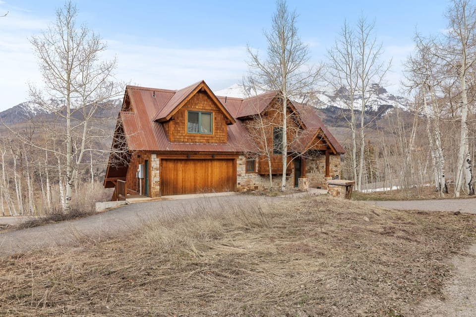 Cozy mountain-inspired living with soaring wood ceilings, a stone fireplace, and stunning floor-to-ceiling views.