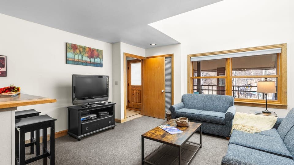 Living room with TV and large window.