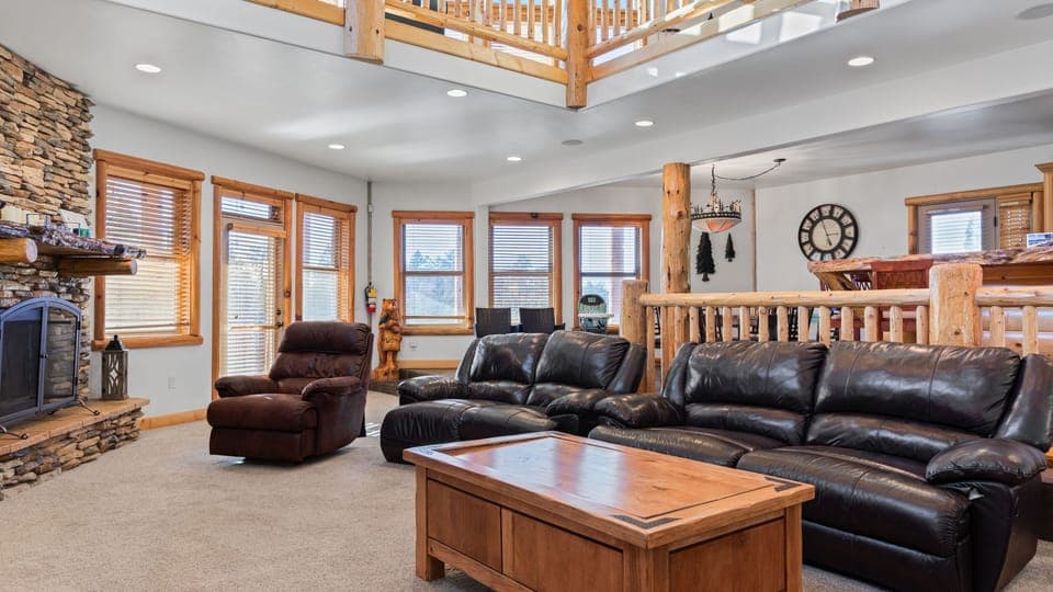 Spacious mountain-style living room with cozy seating, rustic wood accents, and a stone fireplace centerpiece.
