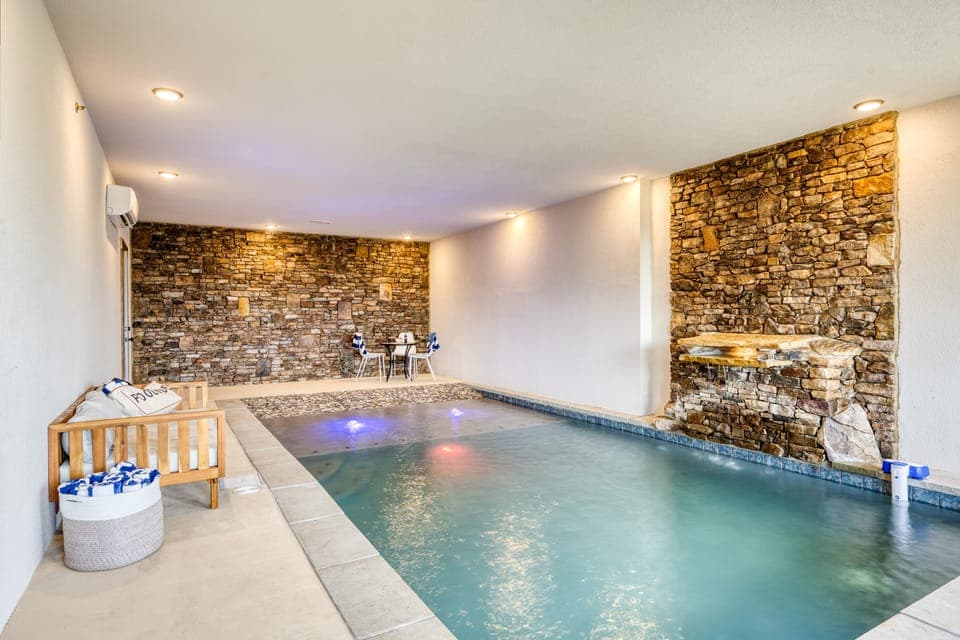 Indoor heated concrete pool features beach entry.