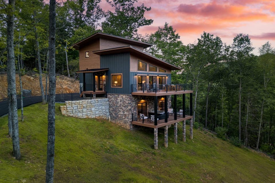 Two-story cabin with deck and forest backdrop
