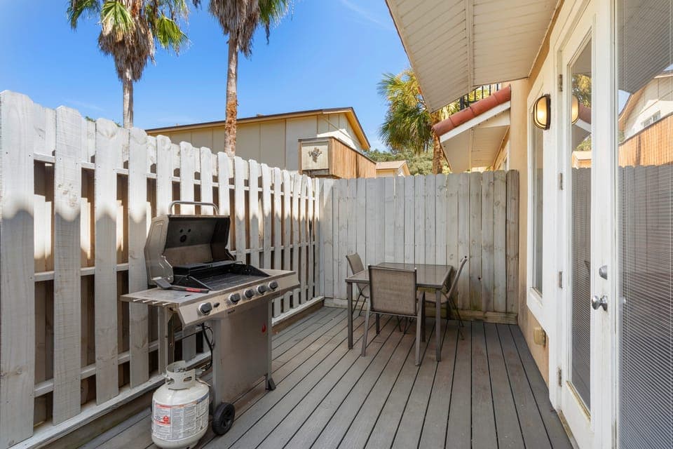 A private patio with a gas grill and outdoor seating, perfect for a sunny day barbecue.