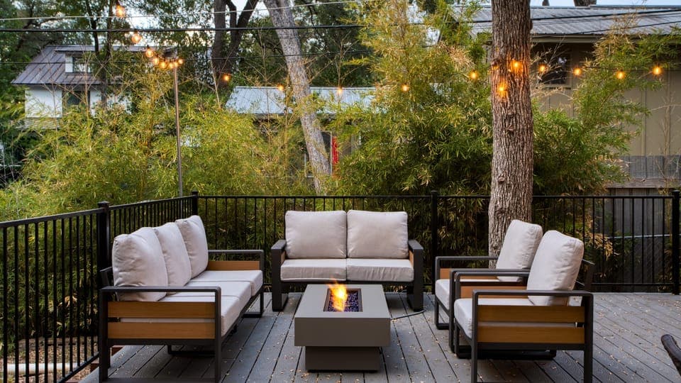 Firepit area with cushioned seating under the trees.