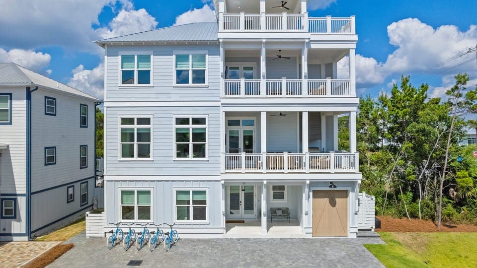 This stunning four-story coastal retreat features three expansive covered balconies and a top-level sun deck, offering endless outdoor living.