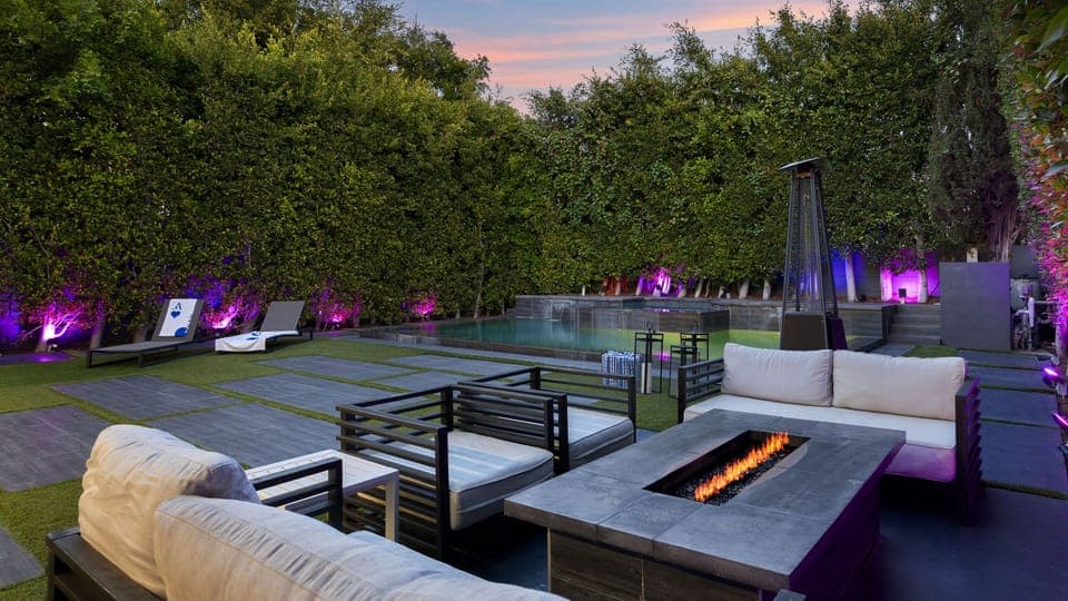 Resort-style backyard with a pool and spa, fire pit lounge, and vibrant evening ambiance.
