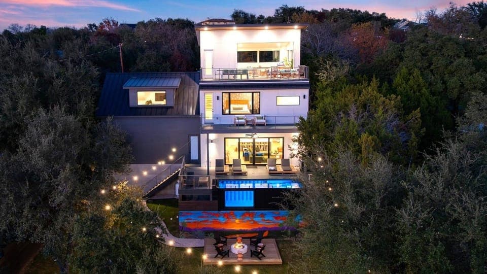 Austin nights shine at this multi-level retreat, with glowing decks, a private pool, and sunset views framed by the trees.