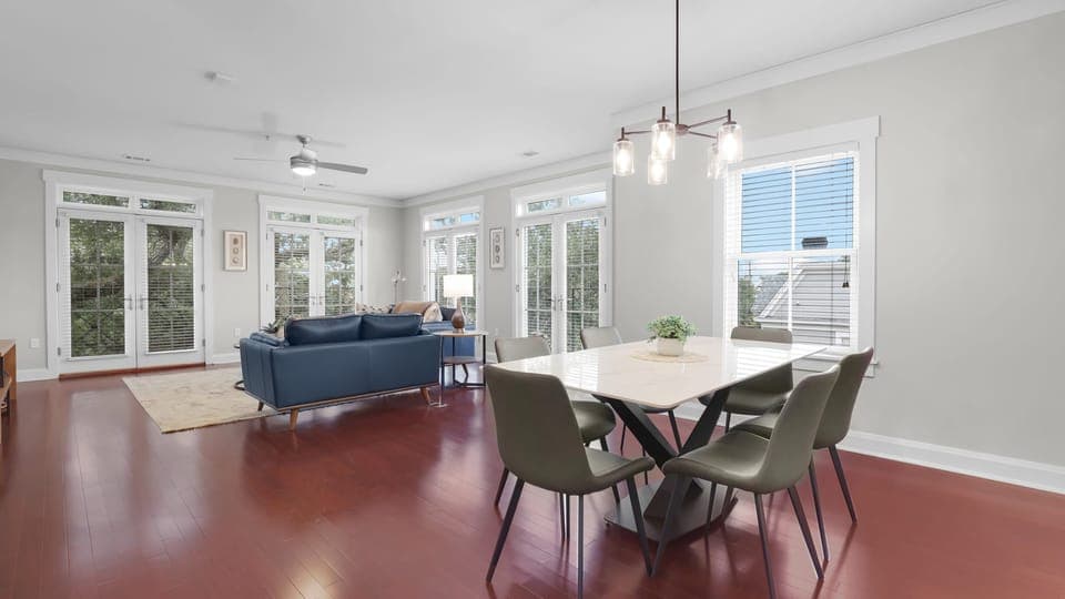 Airy and inviting living-dining space framed by tall windows and contemporary finishes.