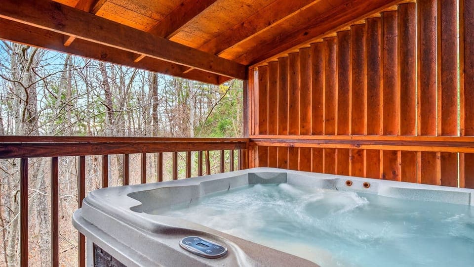 Private covered deck with a relaxing hot tub and forest views.