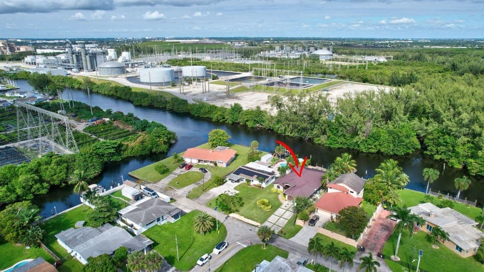 Aerial view of the waterfront home with resort-style pool, and lush tropical surroundings.