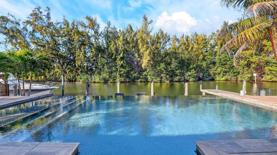 Serene waterfront pool deck overlooking calm waters and lush tropical views.