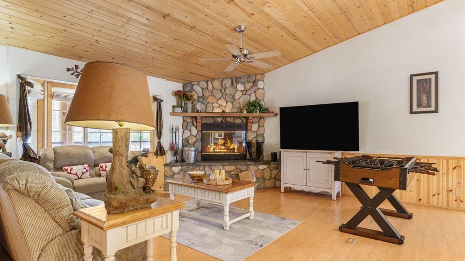 Spacious living area with a stone fireplace, TV, and foosball table for entertainment.