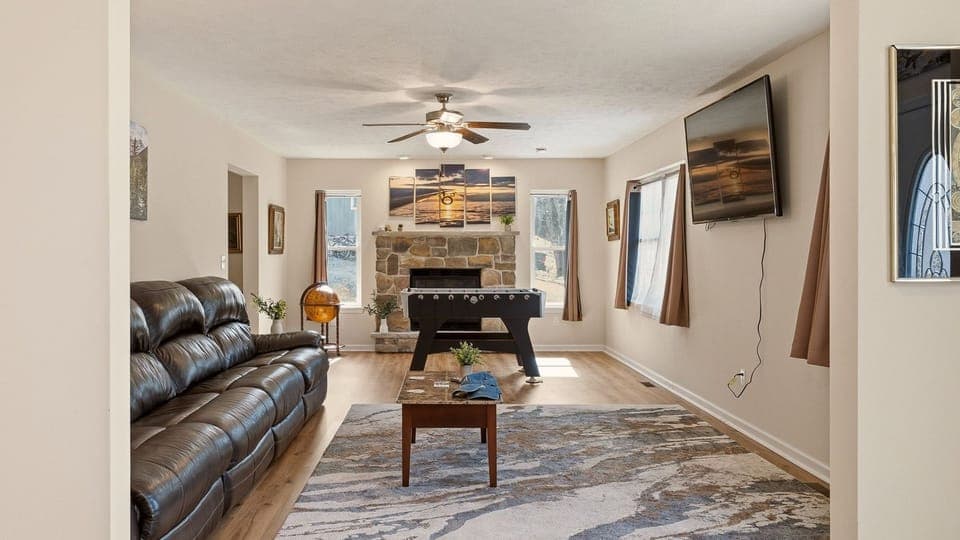 Cozy living room with a leather sectional, stone fireplace, and a foosball table for easy fun.