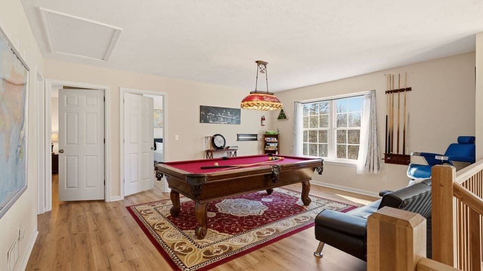 Classic red‑felt pool table, cozy seating, and plenty of natural light.