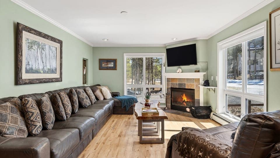 Spacious living area with a leather sectional, fireplace, and flat-screen TV.
