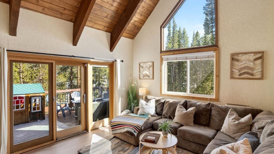 Bright, airy living room with vaulted ceilings, cozy sectional seating, and seamless access to the scenic outdoor deck.