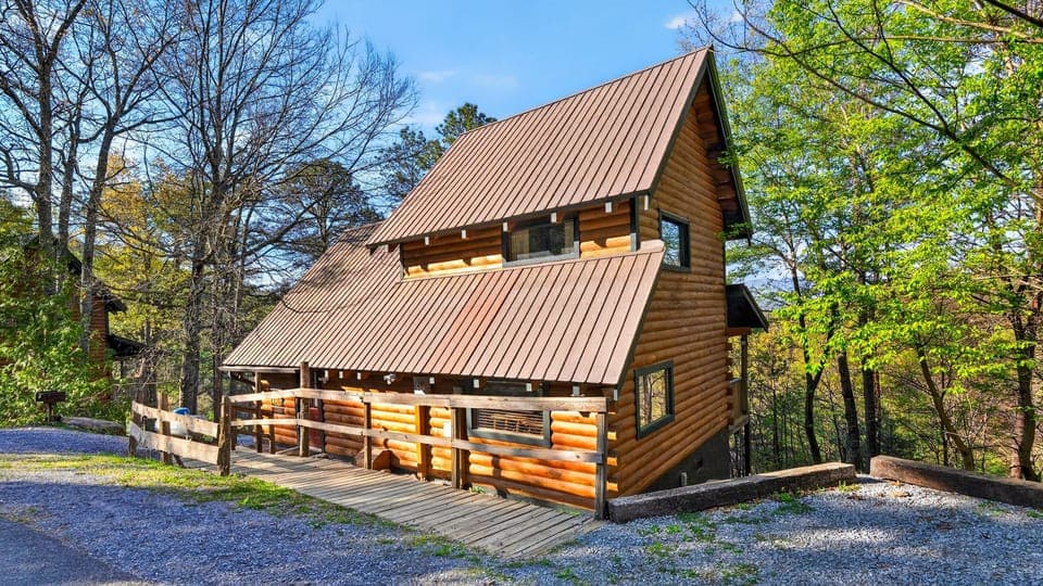 Secluded log cabin with a wide front porch, tucked among tall trees and bathed in bright mountain sunshine.