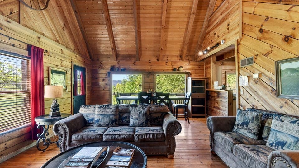 Warm, open-concept living space with vaulted wood ceilings and a queen sleeper sofa—perfect for gathering after a day in the mountains.