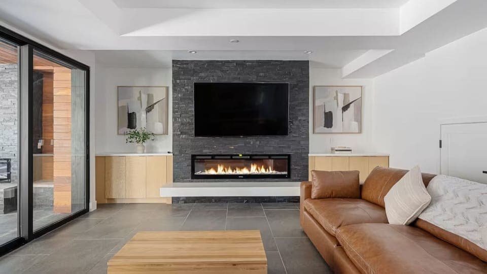 Elegant living room centered by a sleek black stone fireplace and custom built-in cabinetry.
