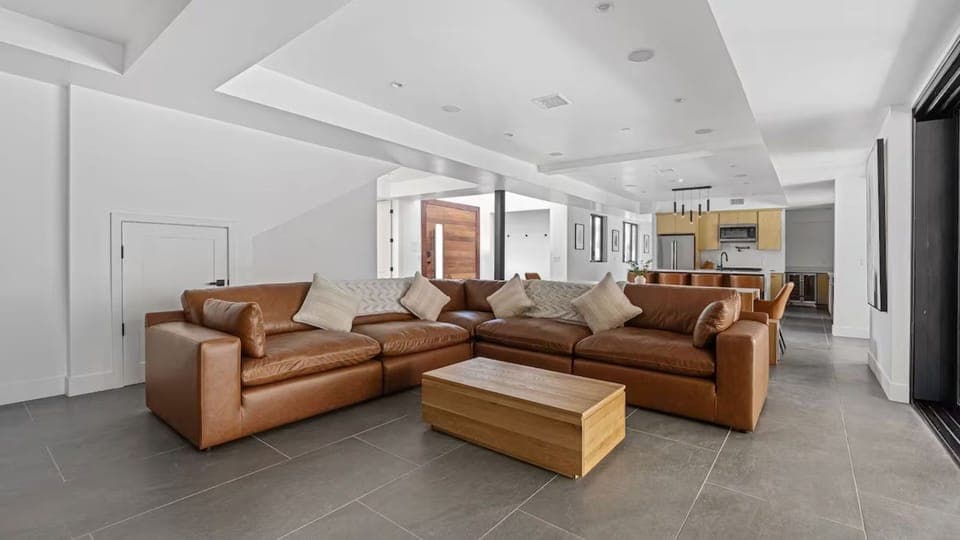 Spacious open-concept living area with a plush leather sectional, perfect for large gatherings.