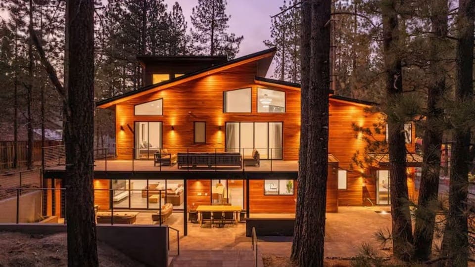 Stunning dusk view of the modern mountain estate, featuring warm wood siding and expansive floor-to-ceiling windows.
