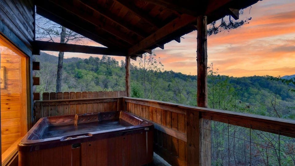 Covered cabin deck with a private hot tub, timber beams, and wide open views of the forested hills. (Jack's Cabin)
