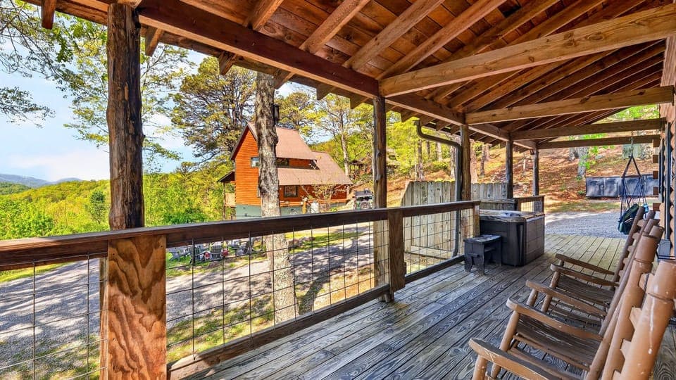 A classic wraparound porch with rocking chairs and a private hot tub—perfect for slow mornings and sunset unwinding in the mountains. (Elijah's Cabin)