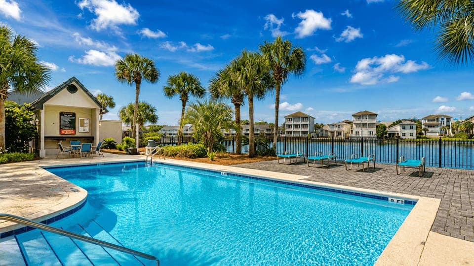 Large community pool surrounded by palm trees and lounging decks.