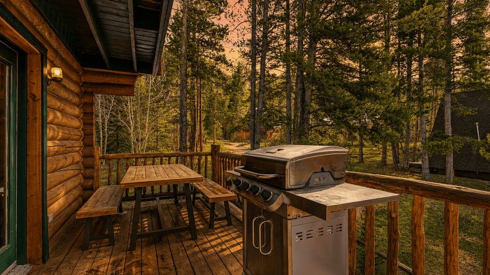 This spacious log cabin great room features soaring ceilings, a cozy stone fireplace, and seamless indoor-outdoor mountain living.
