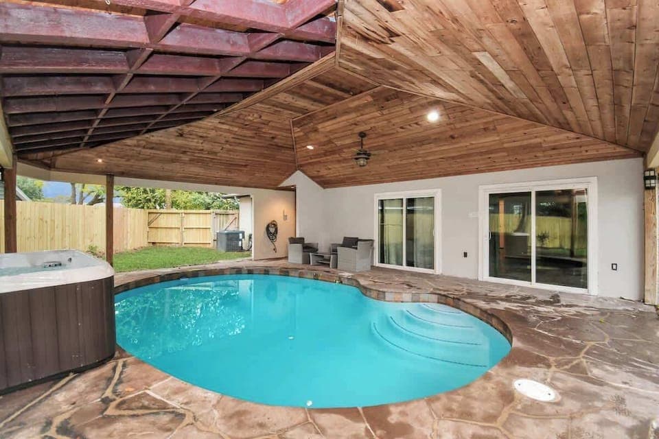 The backyard offers a large covered patio, refreshing pool, relaxing hot tub, patio furniture, and plenty of green grass space to get outside and enjoy the fresh air!