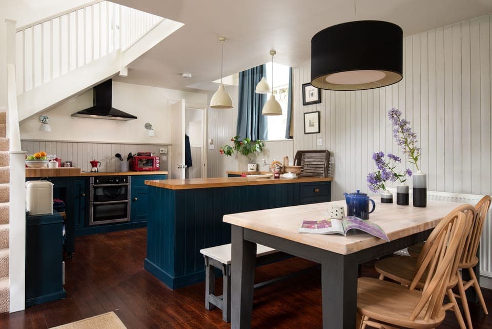The Old School, Hume - dining table with three chairs and bench seating and well equipped kitchen beyond