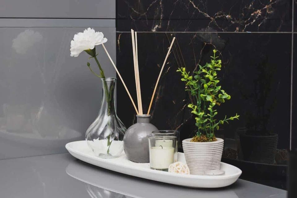 A close-up of a decorative tray with stylish vases, greenery, and candles, contributing to the bathroom's luxurious atmosphere.

