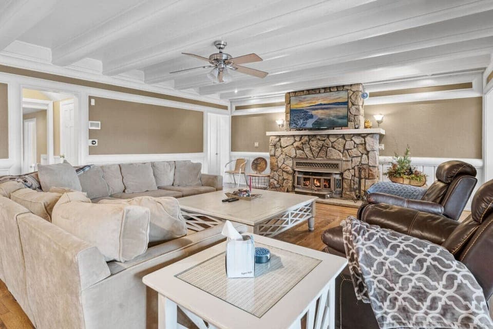 Warm living room w/ plush seating, stone fireplace, and rustic touches for relaxed gatherings.