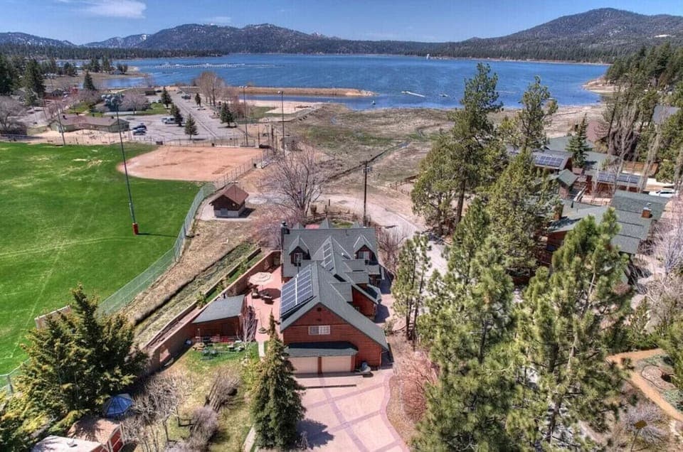Aerial summer view highlighting the cabin, open grounds, and nearby water.
