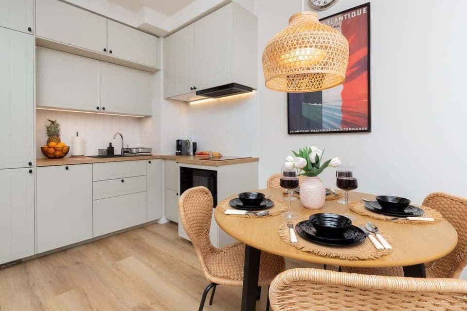 A cozy dining space with a wooden table, black chairs, and a woven pendant light. 