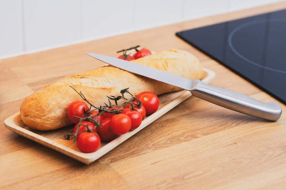 A close-up of a wooden kitchen countertop with fresh bread, tomatoe.