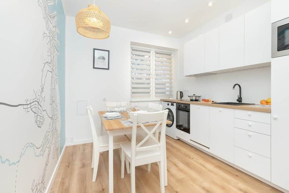 Contemporary kitchen with white cabinets, a dining table set for four, and a light blue accent wall with a stylish map design.
