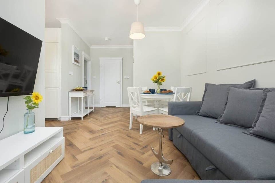 A bright living room with a gray sofa, wooden coffee table, and modern entertainment setup.

