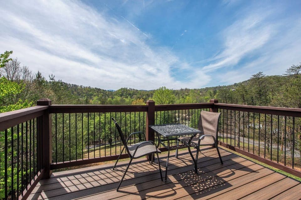 Step onto your private deck and breathe in mountain views that stretch for miles, where morning coffee feels magical at this peaceful table for two.