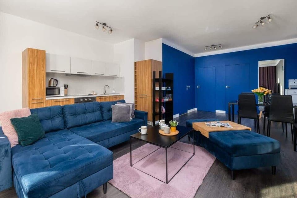 A stylish living room that has one expressive wall in navy blue. The living room is connected to the kitchenette. 