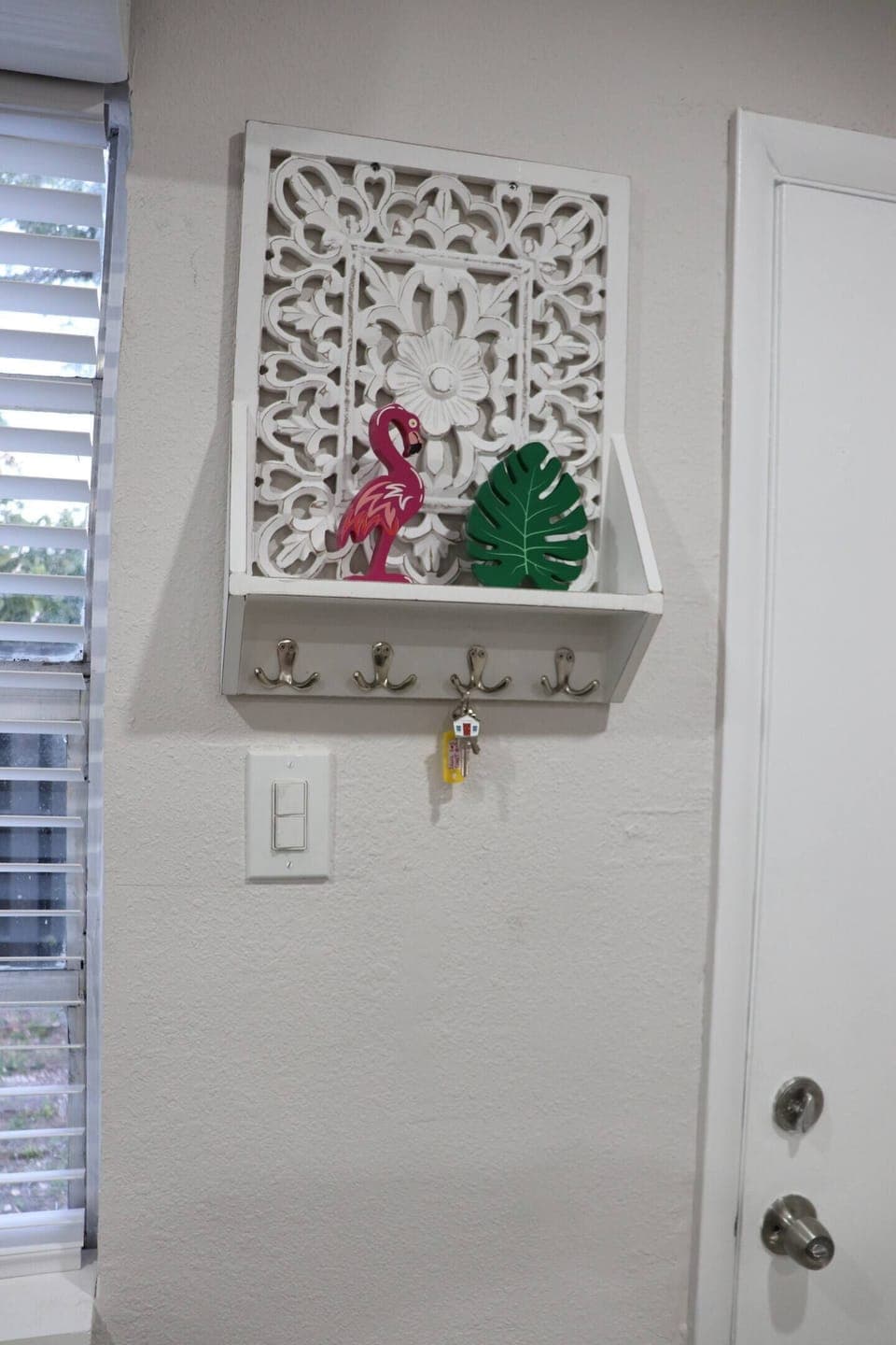 A decorative wall shelf with hooks and tropical accents.
