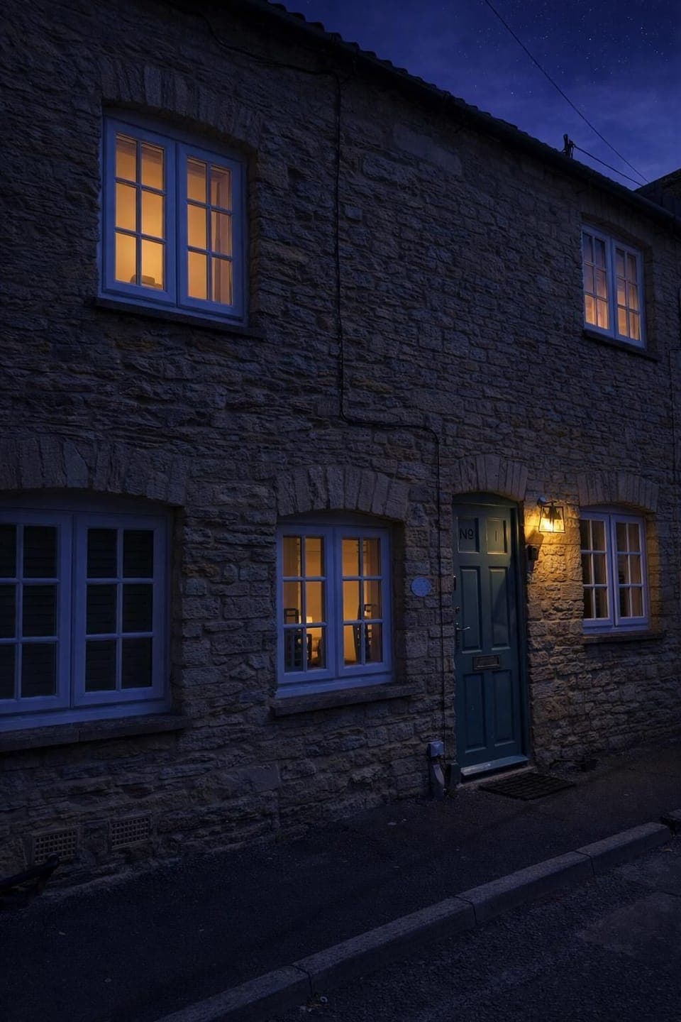 The front of Alexis Cottage at sunset, with golden light catching the stonework and setting the tone for a calm and comfortable stay in the heart of the Cotswolds.