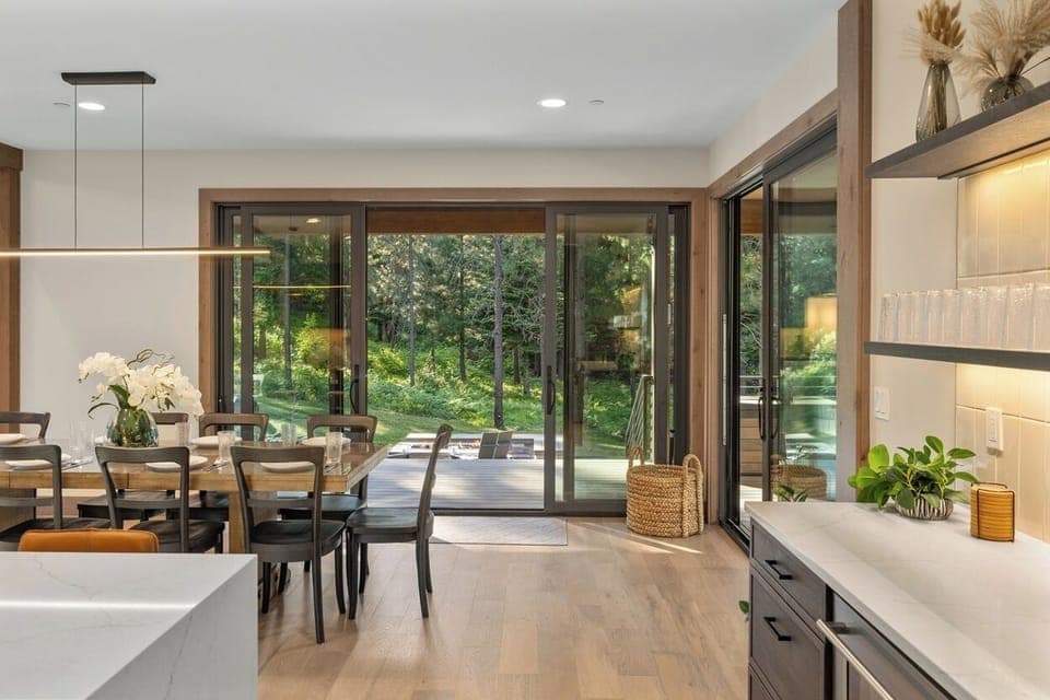 Wall-to-wall sliding glass doors create seamless indoor-outdoor flow from the dining area to the patio lounge.
