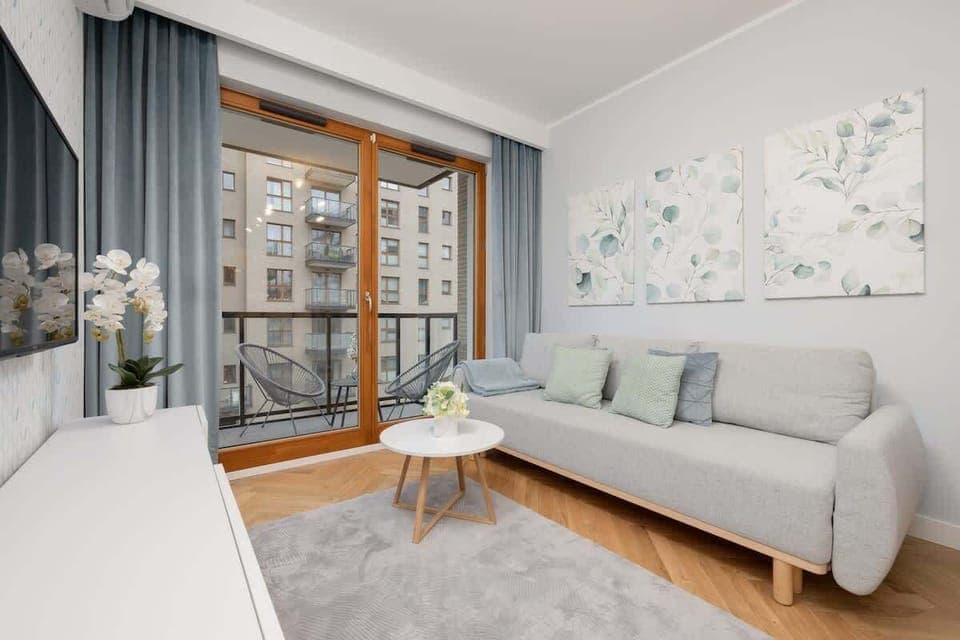 Living room with a double sofa bed, TV, desk with chair, exit to balcony and fully equipped kitchenette