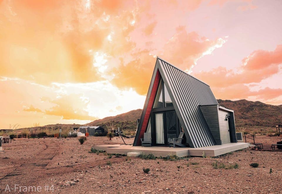 Exterior view of A-Frame #4 front bedroom windows, fire pit, and the wrap-around deck