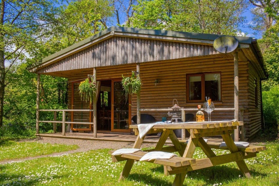 Cabin with wooden veranda area and double glass door entrance, hanging baskets