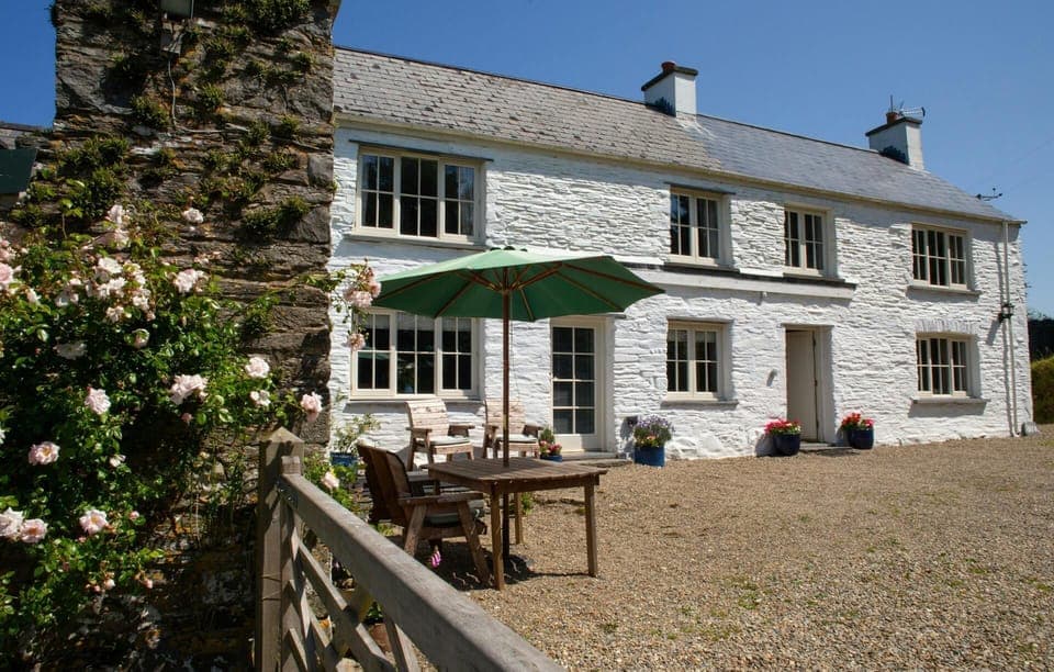 Front of the cottage with garden, chairs and parasol