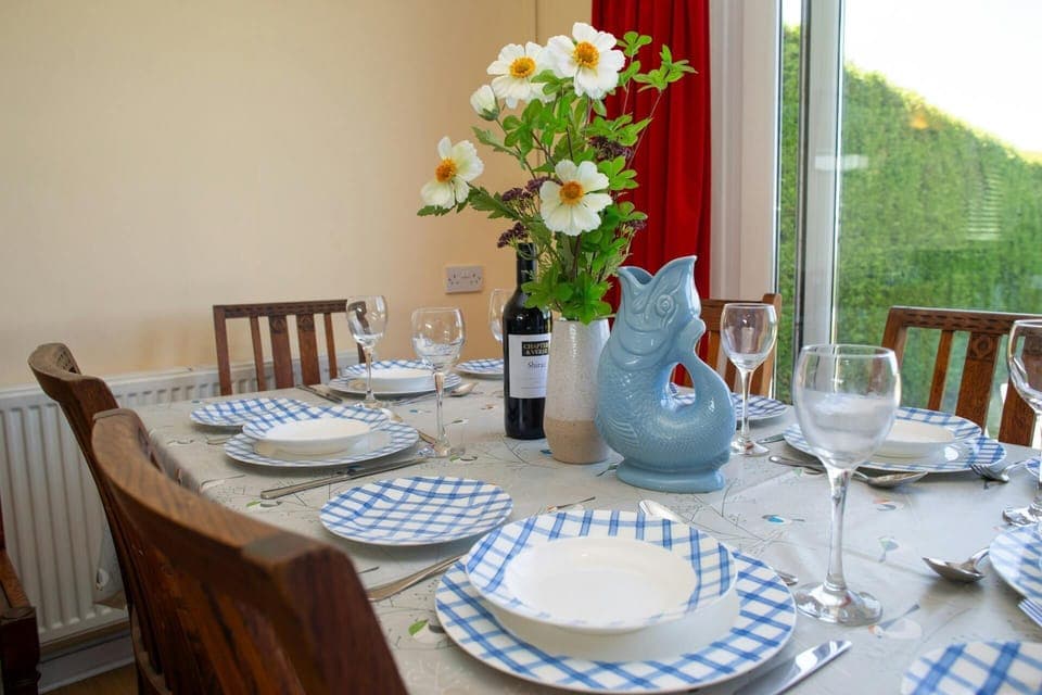 Dining area with table laid for dinner and patio doors leading the garden