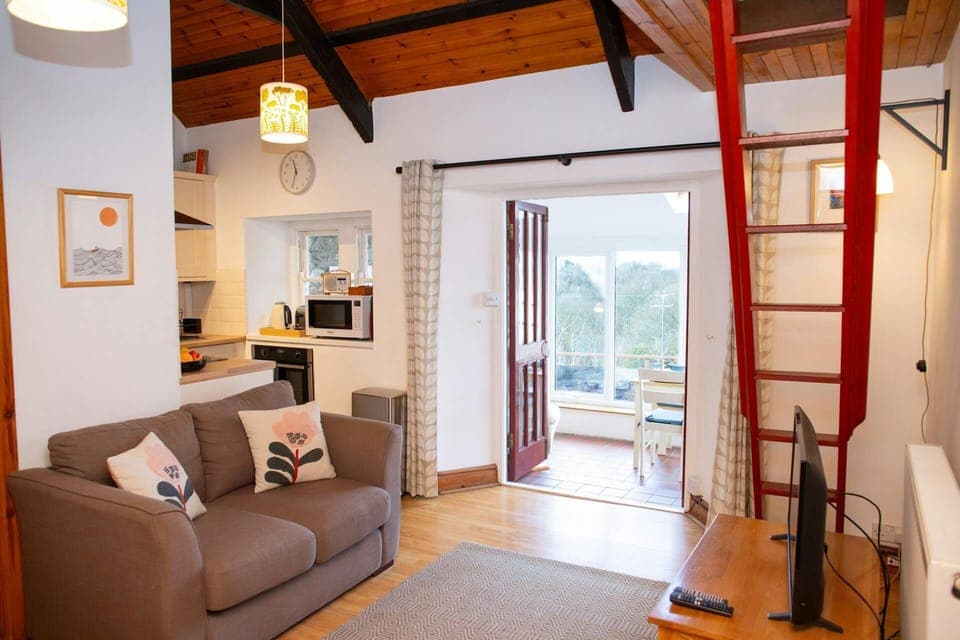 Lounge with steps to mezzanine, sofa, tv, kitchen area