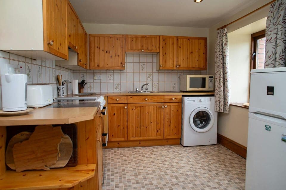 Kitchen with fridge freezer, washing machine, cooker, microwave, kettle and toaster